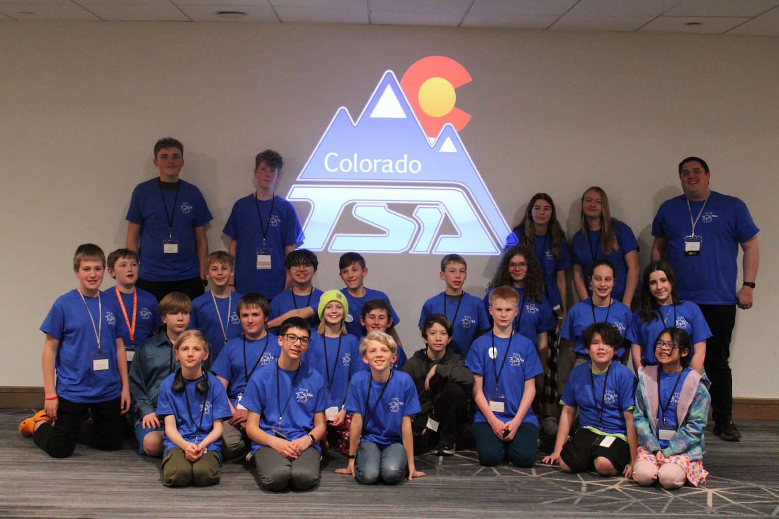 Participants from EMS pose with the Colorado TSA logo against a blank wall.