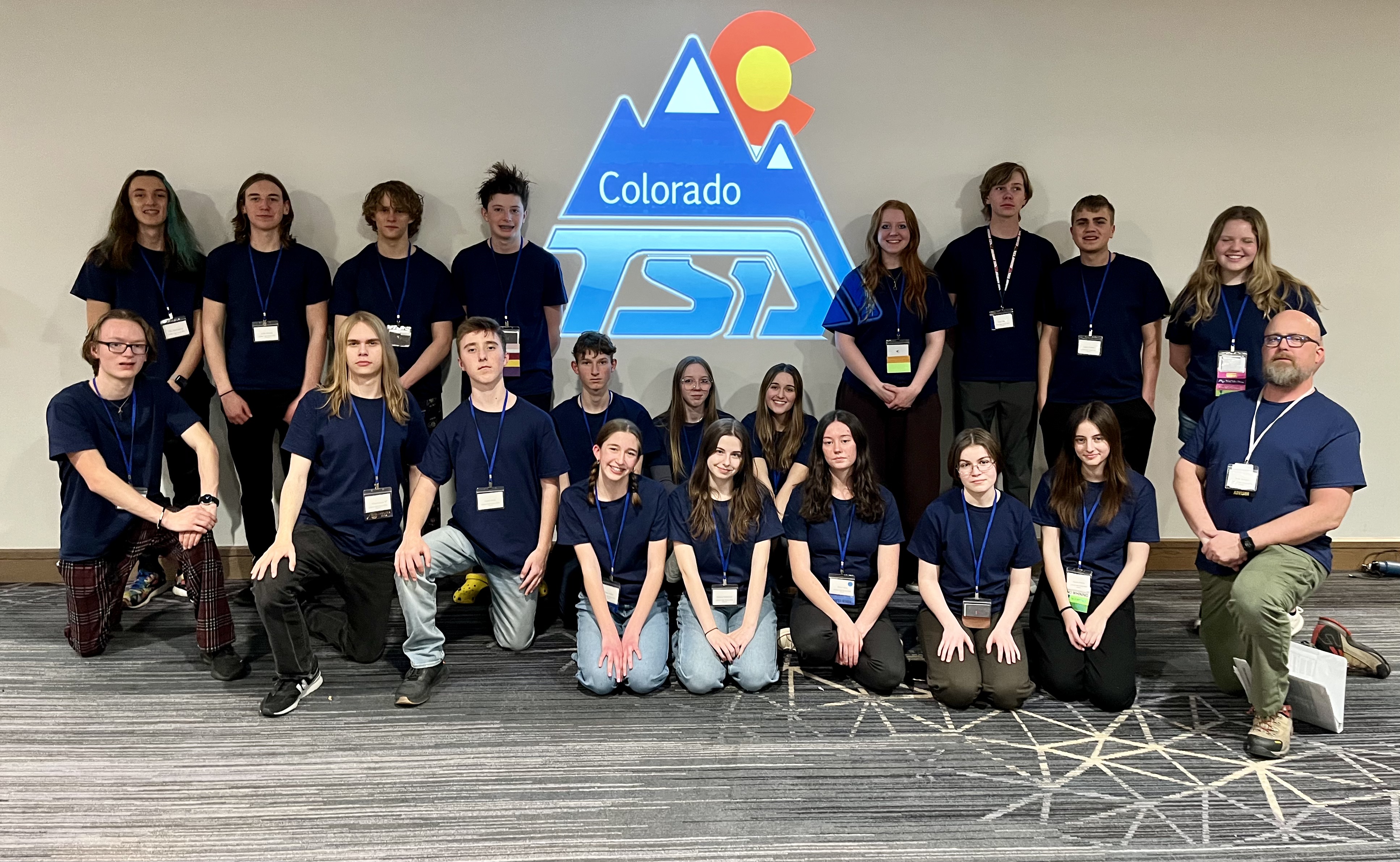 Participants from LHS pose with the Colorado TSA logo against a blank wall.
