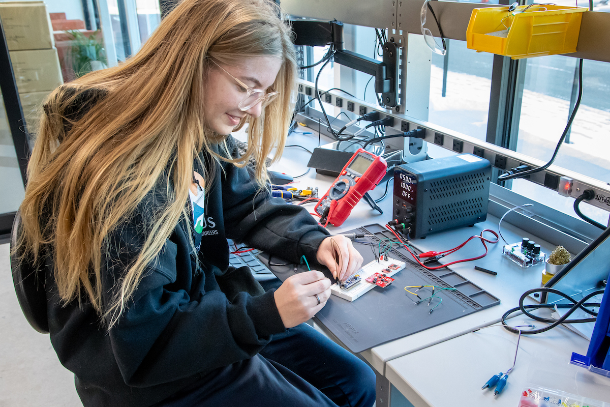 A female student is working on a circuit board project.