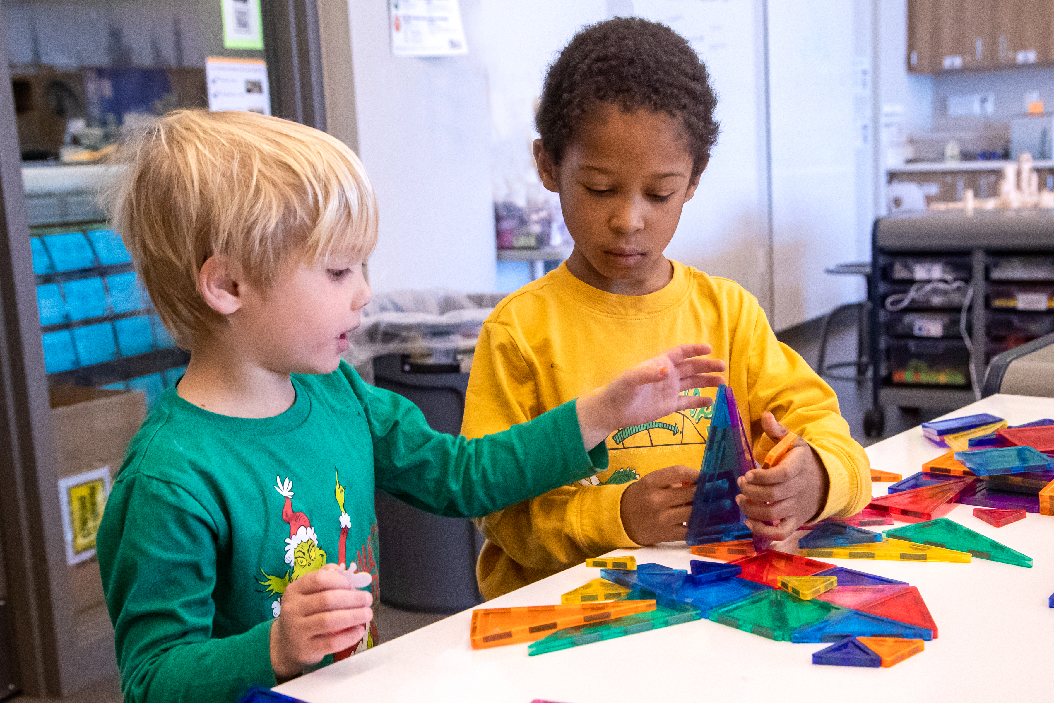 Two elementary students play with magnetic tiles