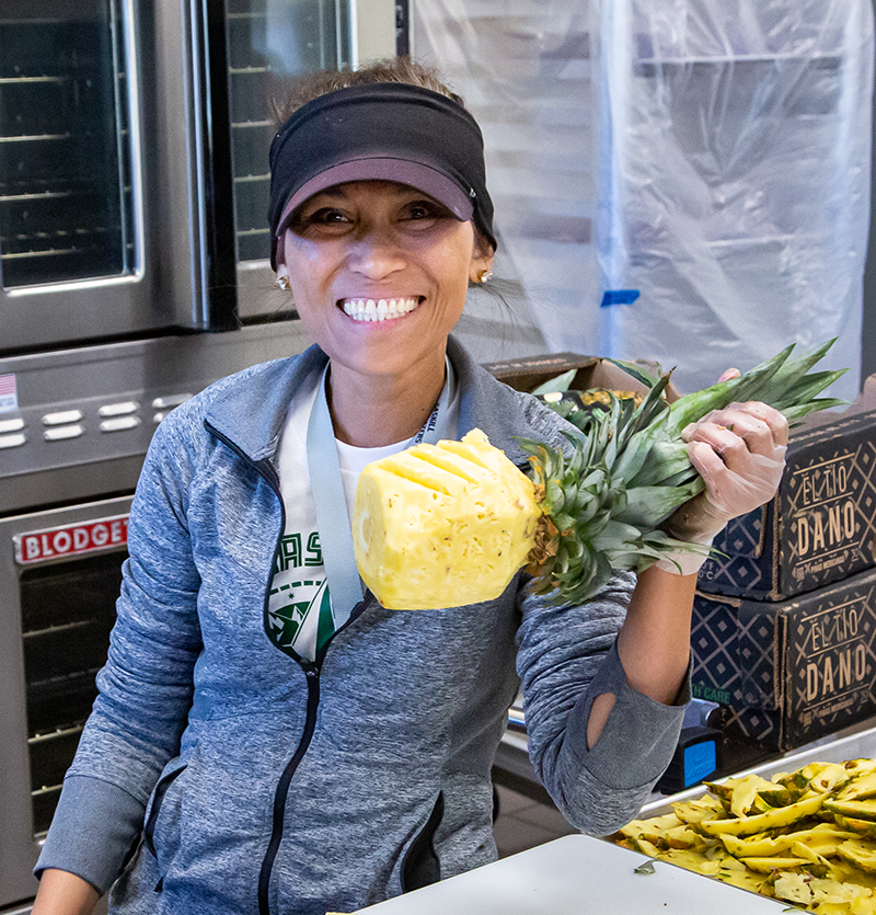 Photo: Nutrition Services employee holding up a pineapple