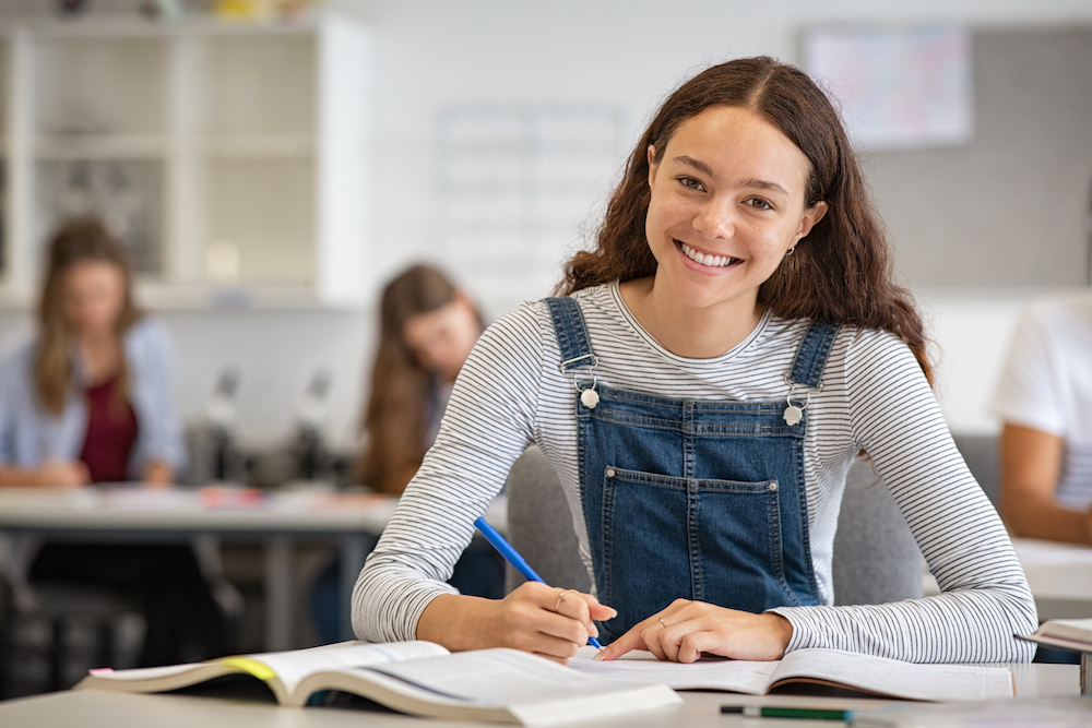 High School girl working at desk, smiling