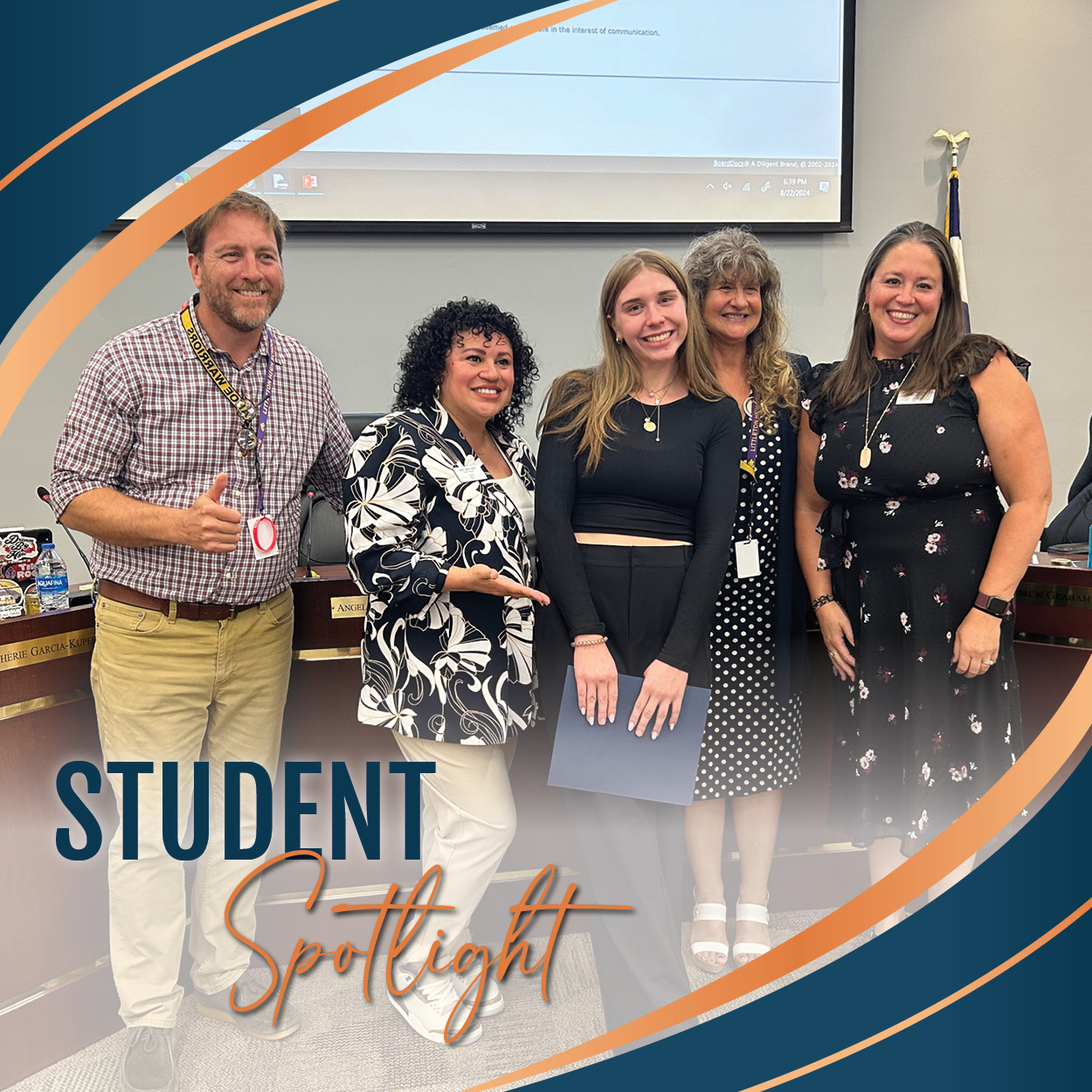 Kate J. holds her Student Spotlight certificate and is surrounded by the LPS Board of Education in the Boardroom.