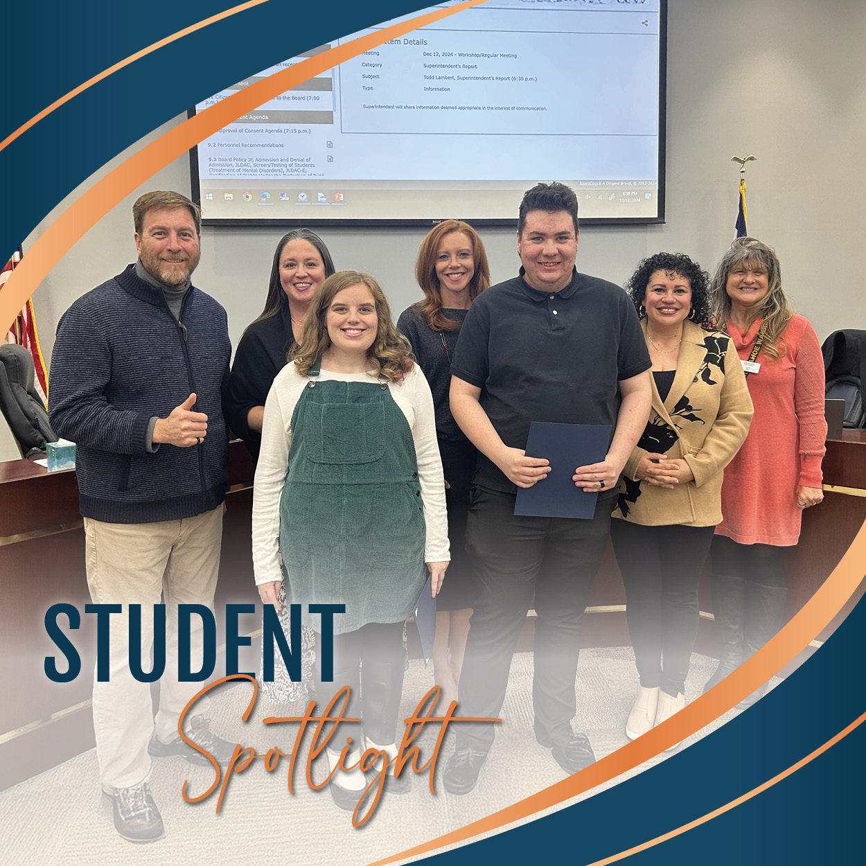 Two students holding certificates stand in front of a group of Board of Education members in a meeting room. The group is smiling, with one Board member giving a thumbs-up. The image is framed with curved blue and orange graphics, and the text 'STUDENT Spotlight' is prominently displayed in the bottom left corner.