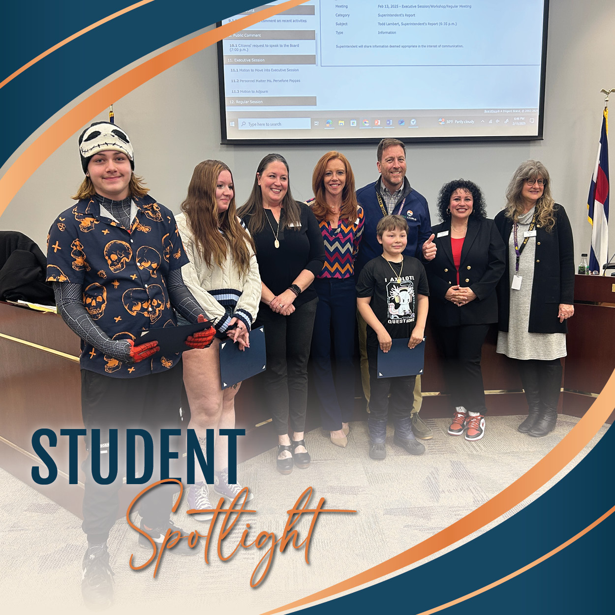 A group of eight people, including students and Board of Education members, pose for a photo in a Board meeting. Three students hold certificates. A projector screen in the background displays a meeting agenda, and a Colorado state flag stands to the side. The image includes a curved graphic overlay with "Student Spotlight" in bold, elegant text.