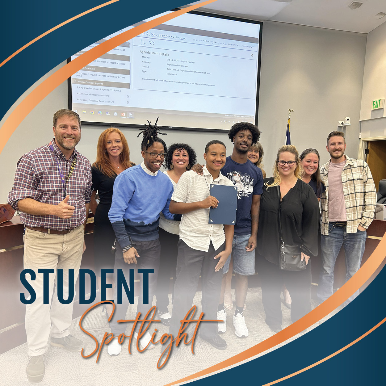 A group of people standing together at an LPS Board of Education meeting. In the center, a smiling student is holding a certificate, and he is surrounded by several adults, including Board of Education members and his family, all celebrating his recognition. A large screen displaying meeting details is visible in the background. The image has a design overlay with the words "Student Spotlight" in bold text across the bottom corner. The atmosphere is one of support and pride.