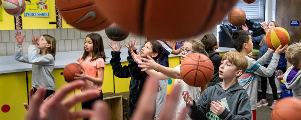elementary age students playing with basketballs